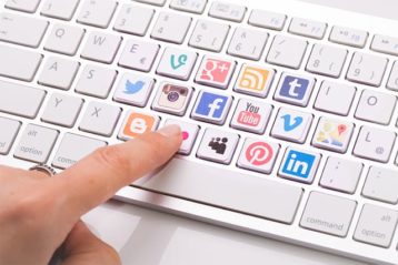 An image featuring a keyboard that has a lot of social media logos on the keys representing social media activities