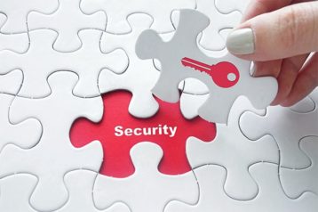 An image featuring a person holding a puzzle that has a red lock key on it and is putting it on top of security representing data security concept